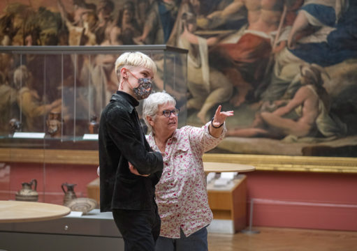 Making Conversation workshop - two people leaning in to talk in front of a painting. The woman has noticed something in the painting and is pointing towards it