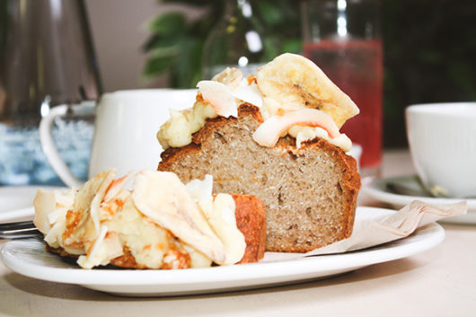 A slice of Banana and Coconut loaf with thick cream cheese frosting
