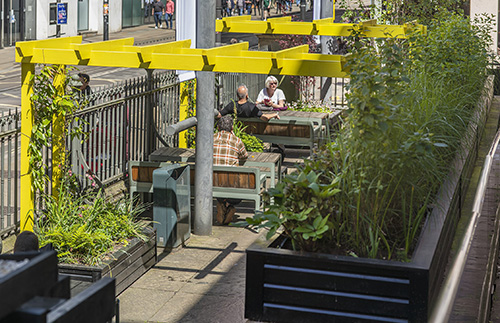view of the Derek Jarman Pocket Park with a few visitors sat on the benches