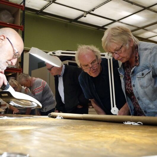 A group leaning in to look at an antique map