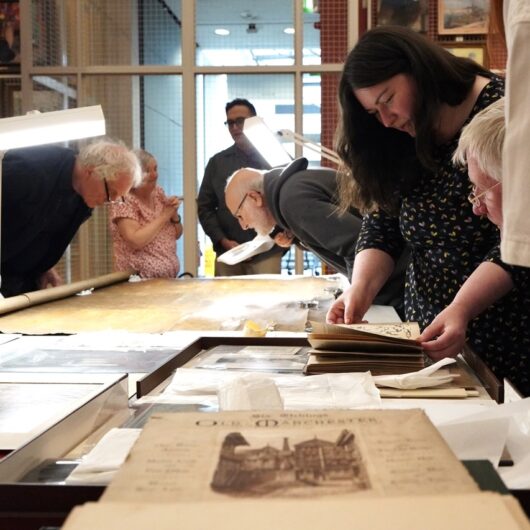 The group leaning over a large table to look at various ephemera