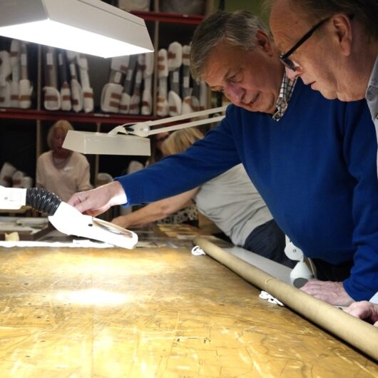 Two men, using a light to get a closer look at details in the map
