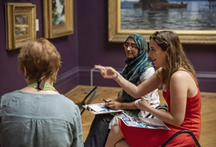 Art Bites - 3 women sat on stools in the gallery having a discussion in front of painting