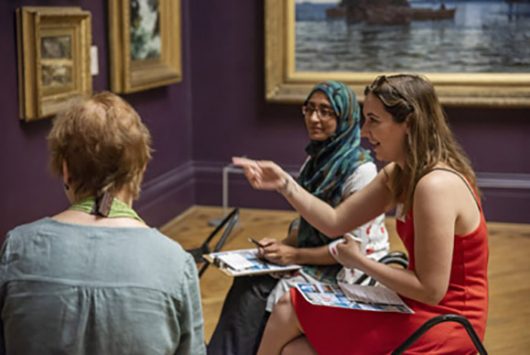 Art Bites - 3 women sat on stools in the gallery having a discussion in front of painting