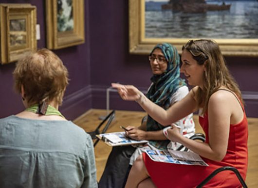 Art Bites - 3 women sat on stools in the gallery having a discussion in front of painting