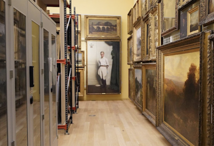 Taking Stock - large paintings hung in salon style to right and metal cabinets to left of an exhibition space